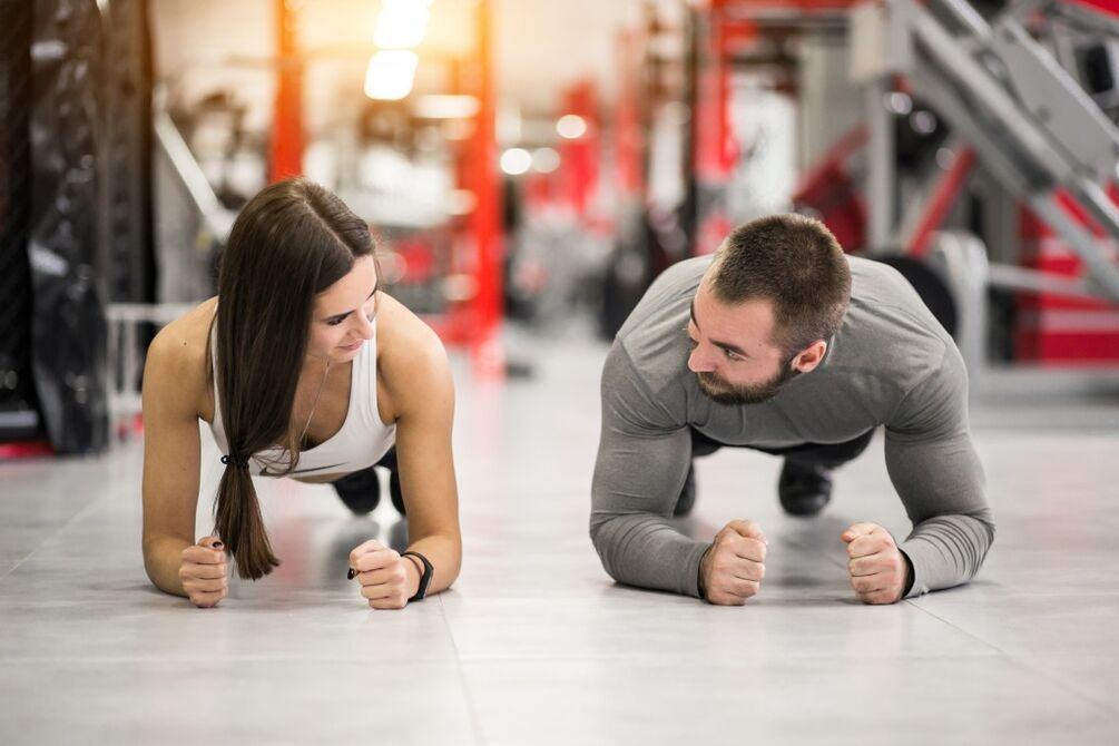 Un bărbat și o femeie efectuează exercițiul plank conceput pentru toate grupele musculare